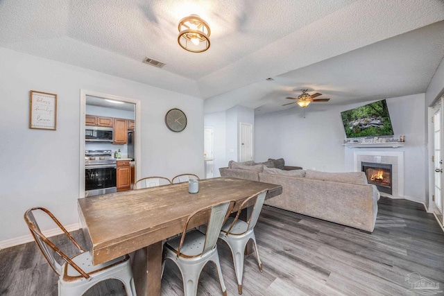 2000 Silverado Rd, Pensacola, FL 32506 - dining space featuring dark wood-style flooring, baseboards, a textured ceiling, a fireplace, and a ceiling fan
