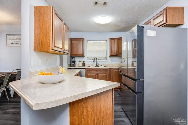 2000 Silverado Rd, Pensacola, FL 32506 - kitchen with freestanding refrigerator, a sink, a textured ceiling, dark wood-type flooring, and a peninsula