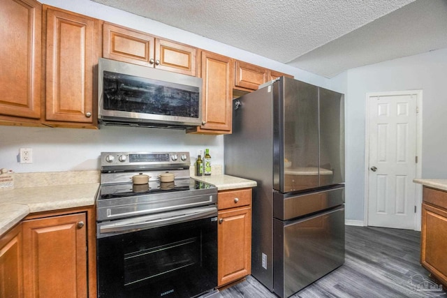 2000 Silverado Rd, Pensacola, FL 32506 - kitchen with appliances with stainless steel finishes, dark wood finished floors, light countertops, brown cabinetry, and a textured ceiling