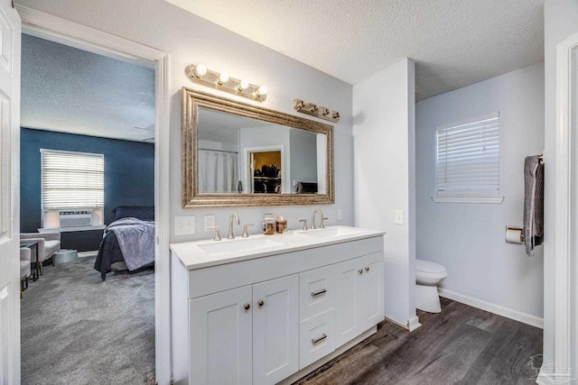 2000 Silverado Rd, Pensacola, FL 32506 - ensuite bathroom with toilet, double vanity, a textured ceiling, wood finished floors, and baseboards