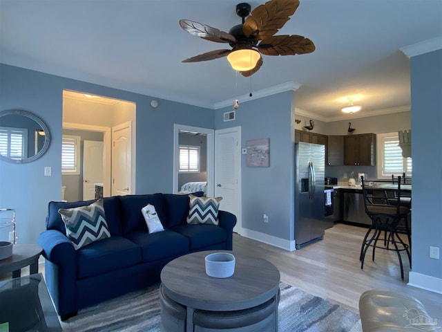 living room with ceiling fan, ornamental molding, and light hardwood / wood-style floors