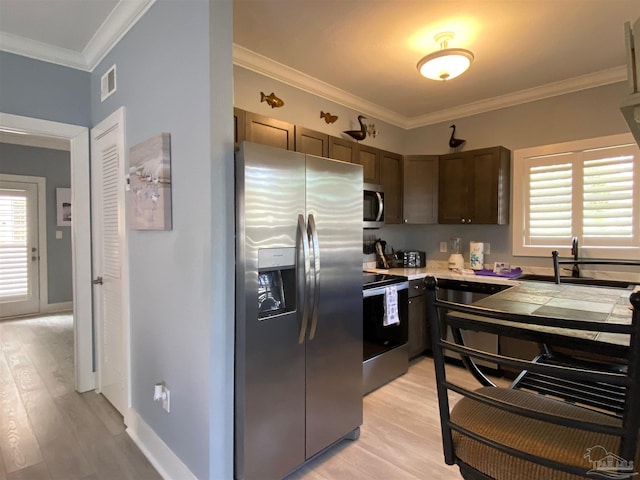 kitchen featuring sink, crown molding, appliances with stainless steel finishes, a wealth of natural light, and light hardwood / wood-style floors