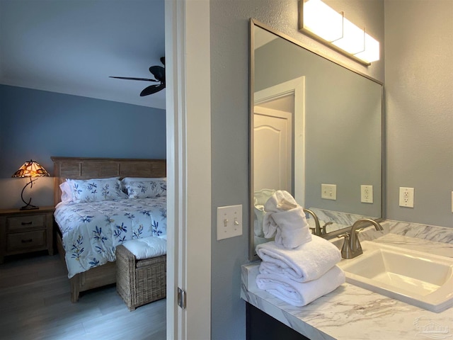 bedroom with hardwood / wood-style flooring, ceiling fan, and sink