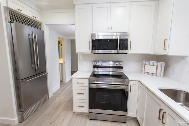 kitchen with light hardwood / wood-style flooring, stainless steel appliances, white cabinetry, and tasteful backsplash