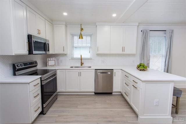 kitchen featuring white cabinetry, a breakfast bar area, a peninsula, stainless steel appliances, and a sink