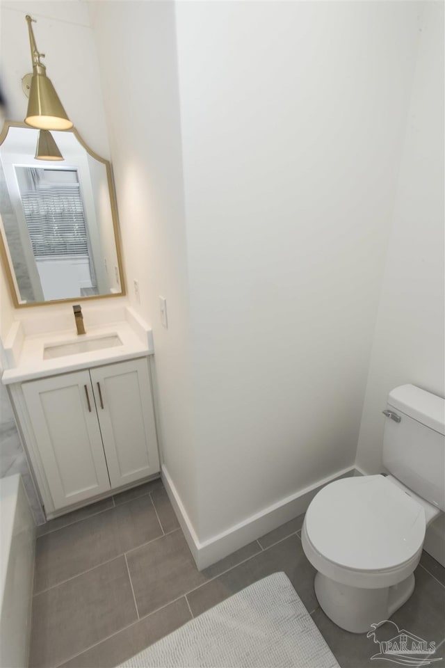 bathroom featuring baseboards, toilet, and vanity