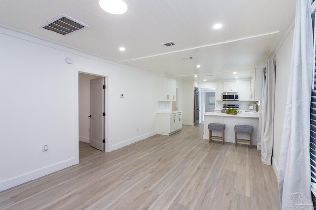 unfurnished living room with light wood finished floors, visible vents, recessed lighting, and baseboards