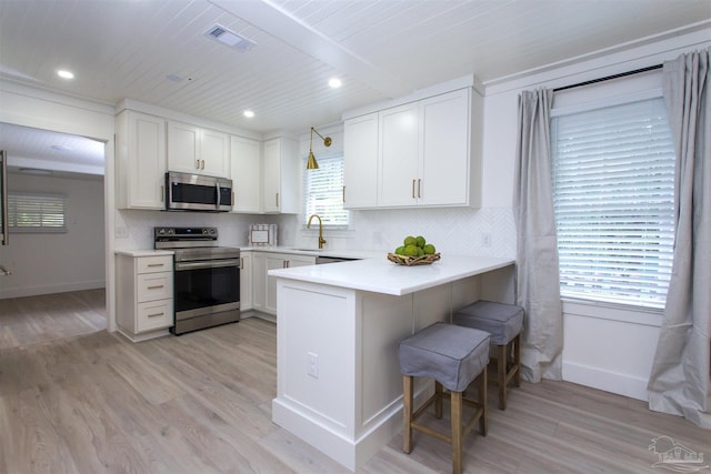 kitchen with tasteful backsplash, a breakfast bar, light wood-style flooring, stainless steel appliances, and a sink