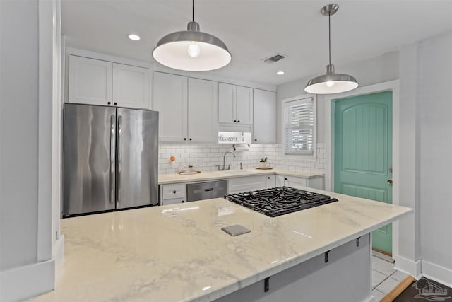 kitchen with white cabinetry, stainless steel appliances, hanging light fixtures, and light stone counters