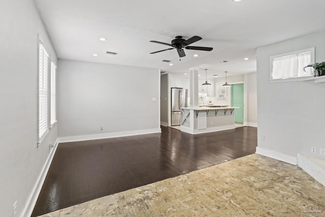 unfurnished living room featuring dark hardwood / wood-style flooring, ceiling fan, and a healthy amount of sunlight