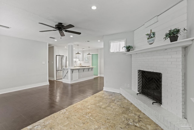 unfurnished living room featuring ceiling fan, a fireplace, and dark hardwood / wood-style flooring