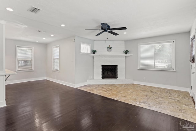 unfurnished living room with a fireplace, dark hardwood / wood-style floors, and ceiling fan