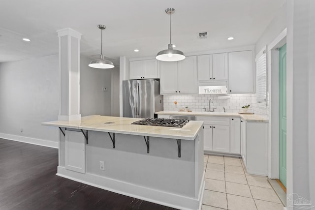 kitchen with pendant lighting, sink, white cabinets, and appliances with stainless steel finishes