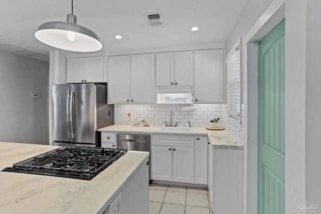 kitchen featuring sink, tasteful backsplash, hanging light fixtures, appliances with stainless steel finishes, and white cabinets