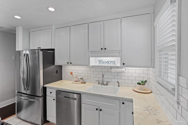 kitchen with white cabinetry, appliances with stainless steel finishes, sink, and backsplash