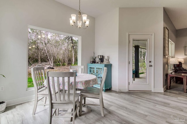 dining space with wood finished floors, a healthy amount of sunlight, and a chandelier