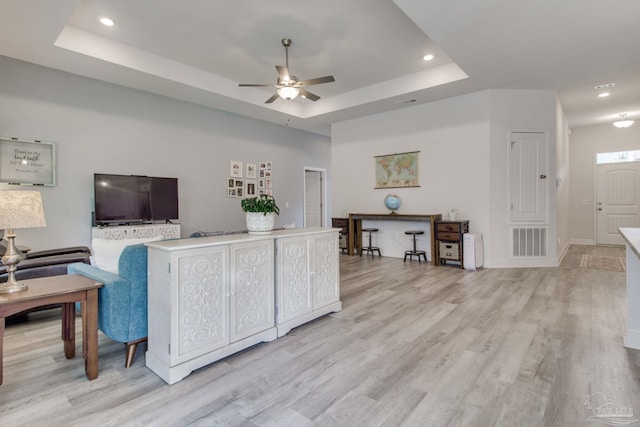 living room featuring light wood-type flooring, visible vents, a ceiling fan, a tray ceiling, and recessed lighting