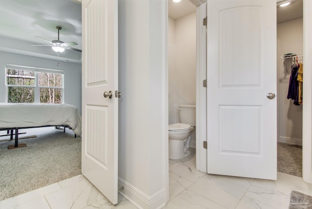 bathroom with toilet, a ceiling fan, marble finish floor, and baseboards