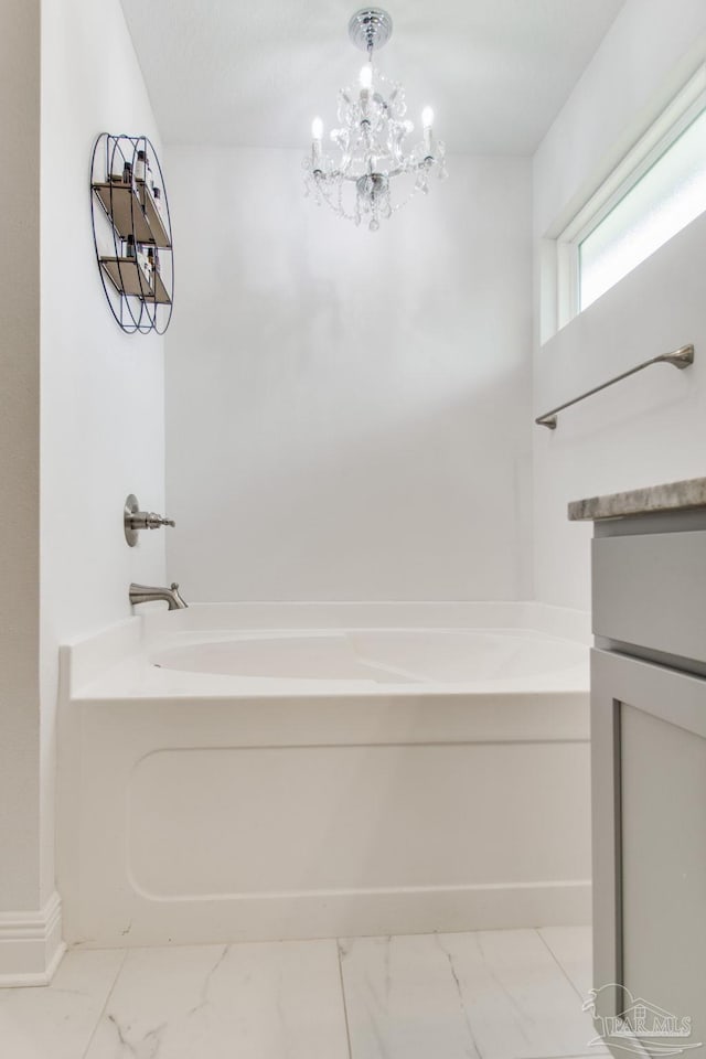 full bathroom featuring a bath, a notable chandelier, marble finish floor, and vanity