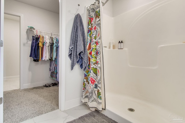 bathroom featuring baseboards, marble finish floor, and a stall shower