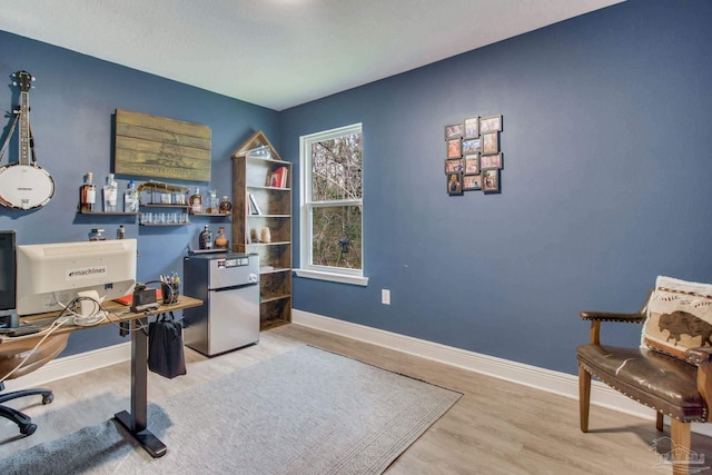 home office with baseboards and wood finished floors