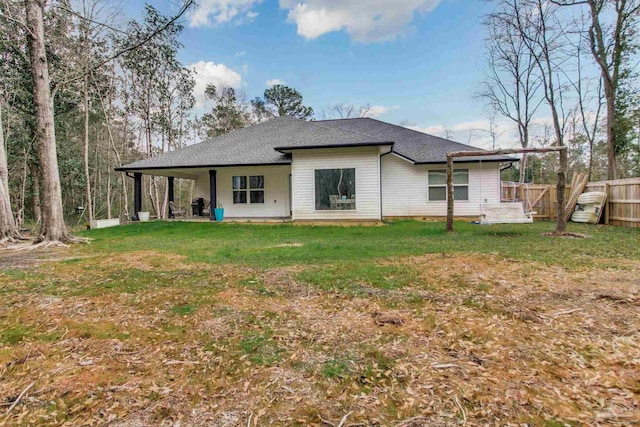 rear view of property featuring a lawn, roof with shingles, and fence