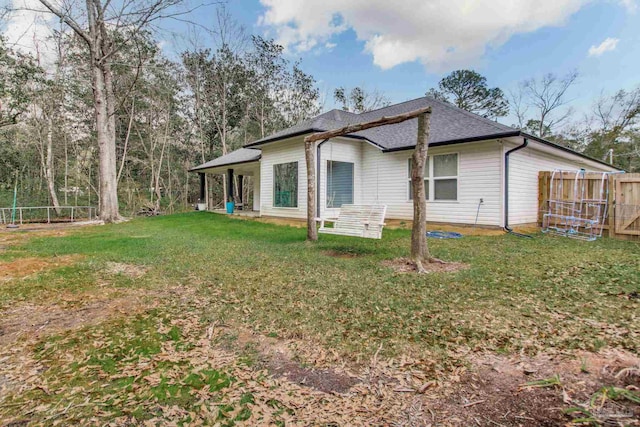 view of home's exterior with fence, a lawn, and roof with shingles