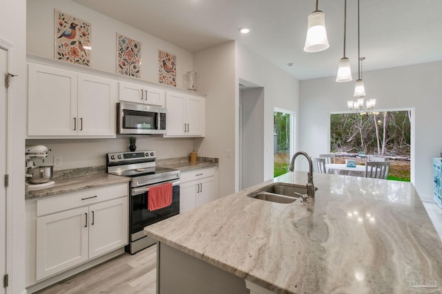 kitchen with white cabinetry, hanging light fixtures, appliances with stainless steel finishes, and a sink