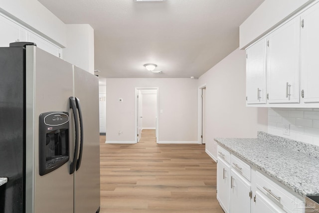 kitchen with stainless steel fridge, white cabinetry, tasteful backsplash, light stone countertops, and light hardwood / wood-style floors