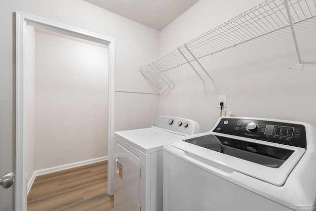 laundry room featuring washer and clothes dryer and light hardwood / wood-style flooring