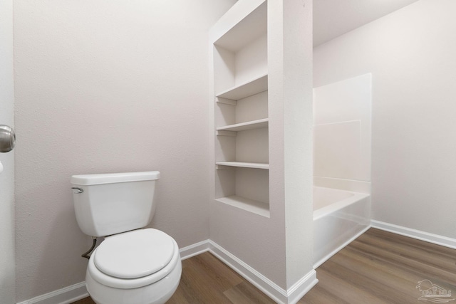 bathroom featuring a bathtub, hardwood / wood-style flooring, built in features, and toilet