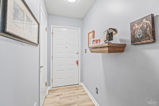 doorway to outside with a textured ceiling and light wood-type flooring