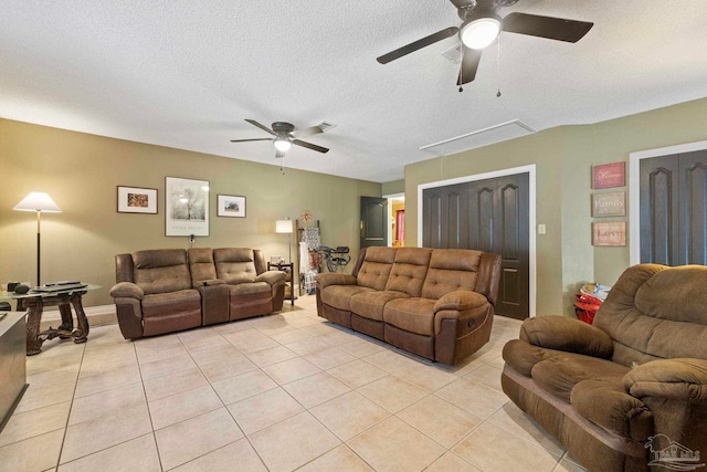 living room featuring attic access, light tile patterned floors, a ceiling fan, and a textured ceiling