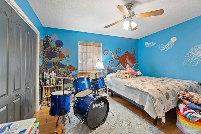 bedroom with a ceiling fan, wood finished floors, and a textured ceiling