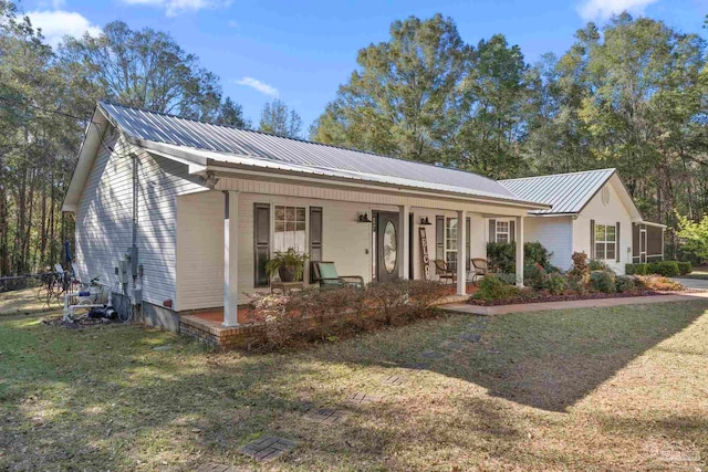 ranch-style house featuring metal roof, covered porch, a front yard, and fence