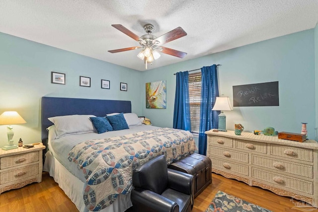 bedroom with ceiling fan, wood finished floors, and a textured ceiling