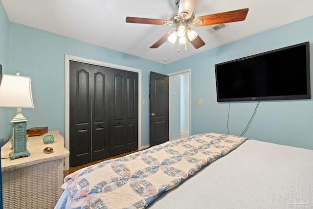 bedroom with wood finished floors, visible vents, a closet, and ceiling fan