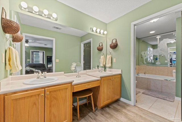 ensuite bathroom with double vanity, a textured ceiling, ensuite bath, and a sink