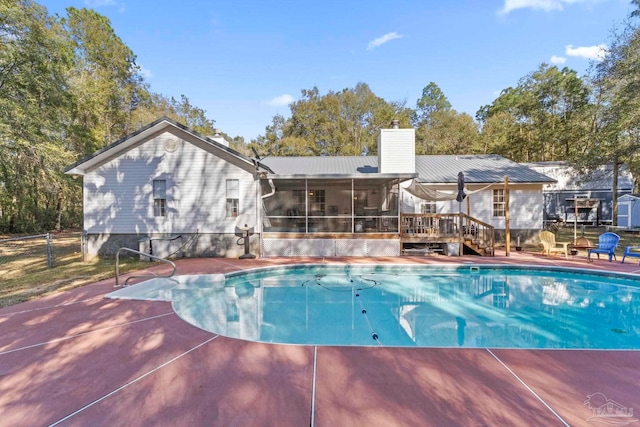 pool featuring a wooden deck, fence, and a sunroom