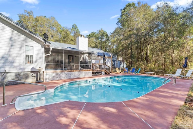 pool featuring a wooden deck, a patio, and a sunroom