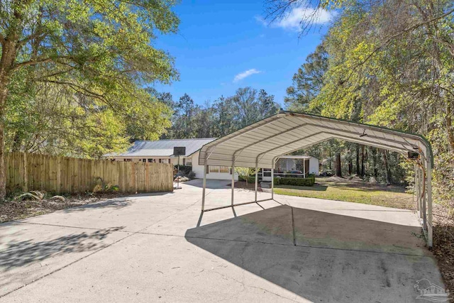 view of vehicle parking with a carport, fence, and driveway