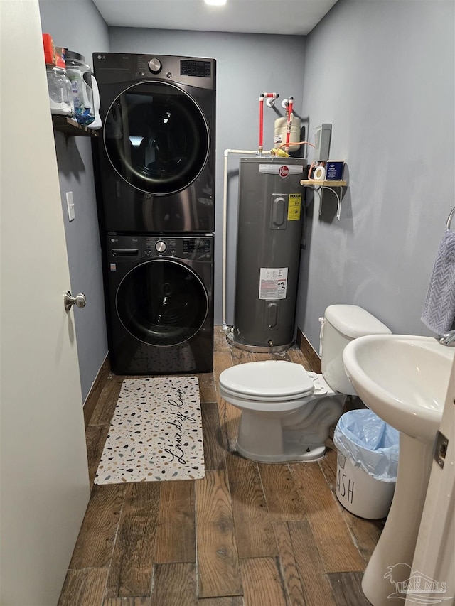 bathroom with toilet, stacked washer and clothes dryer, wood finished floors, water heater, and baseboards