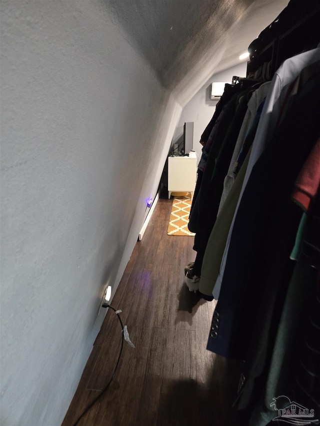 corridor with lofted ceiling, wood finished floors, and a textured ceiling