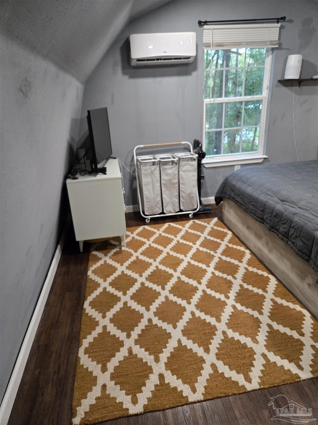 bedroom featuring a wall unit AC, wood finished floors, baseboards, and vaulted ceiling