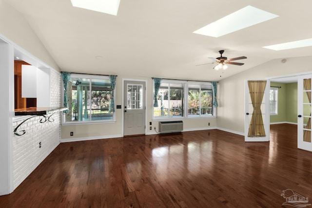 unfurnished living room with dark hardwood / wood-style flooring, a wall unit AC, ceiling fan, and vaulted ceiling with skylight