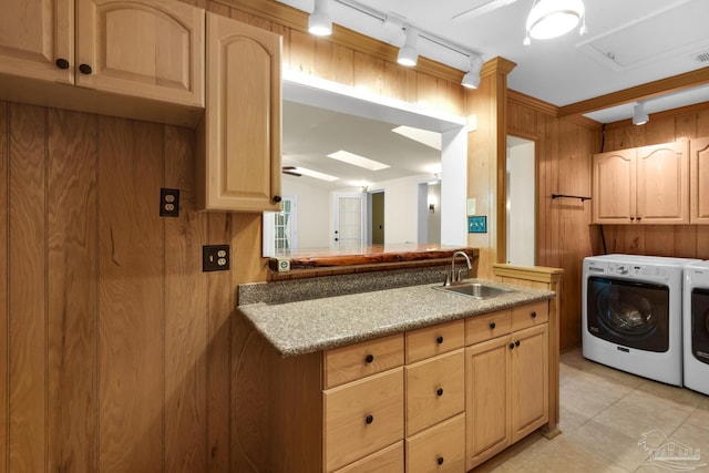 kitchen featuring washer and clothes dryer, wood walls, sink, rail lighting, and light brown cabinetry