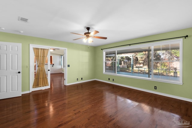 empty room featuring plenty of natural light, ceiling fan, and dark wood-type flooring