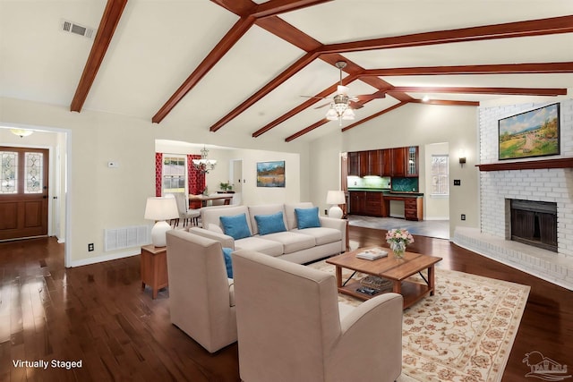 living room featuring vaulted ceiling with beams, a brick fireplace, plenty of natural light, and dark wood-type flooring