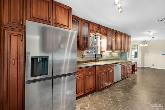 kitchen featuring appliances with stainless steel finishes, tasteful backsplash, sink, decorative light fixtures, and dark tile patterned flooring