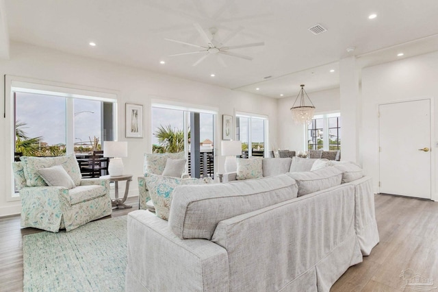 living area with visible vents, recessed lighting, ceiling fan with notable chandelier, and light wood-style floors